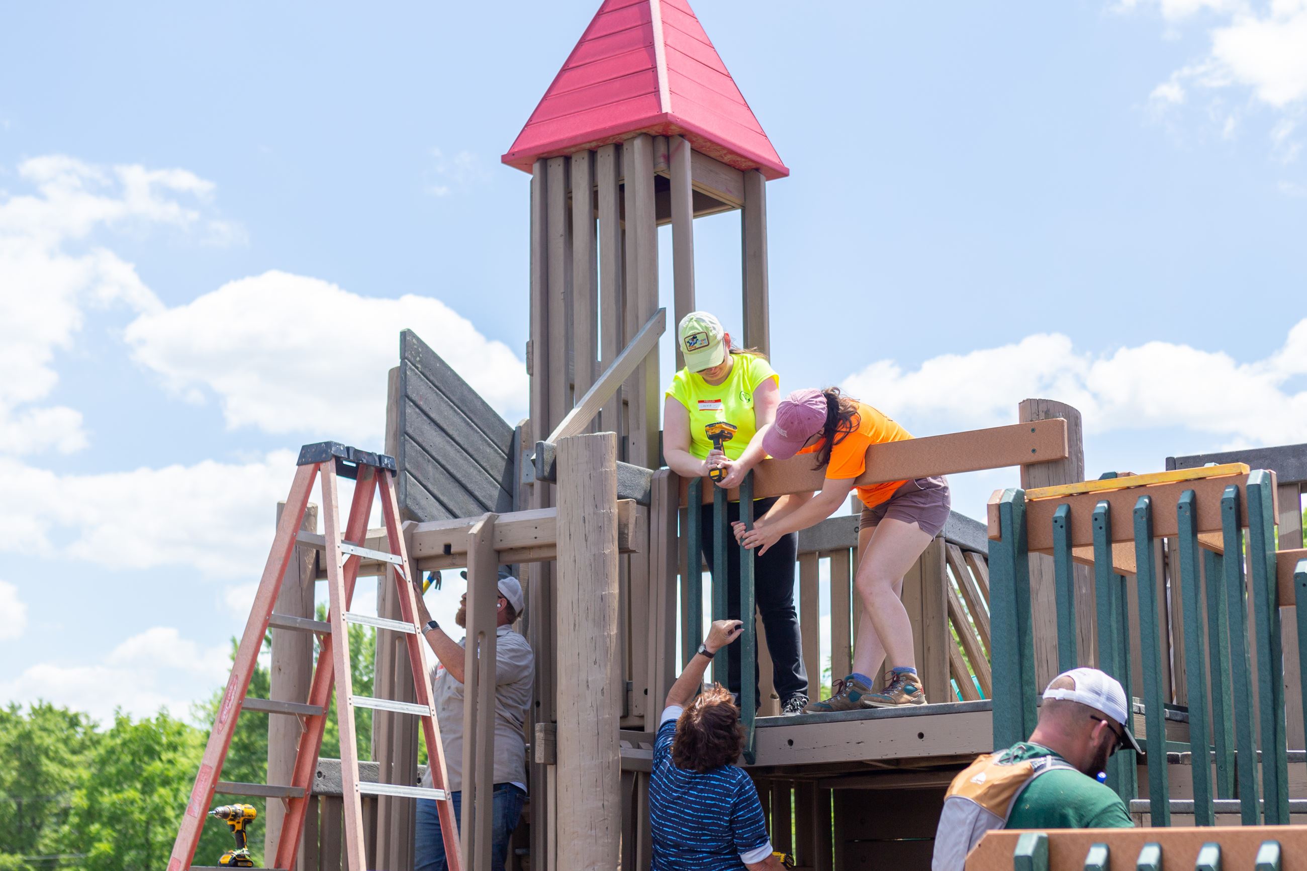 Volunteers attach board to playground